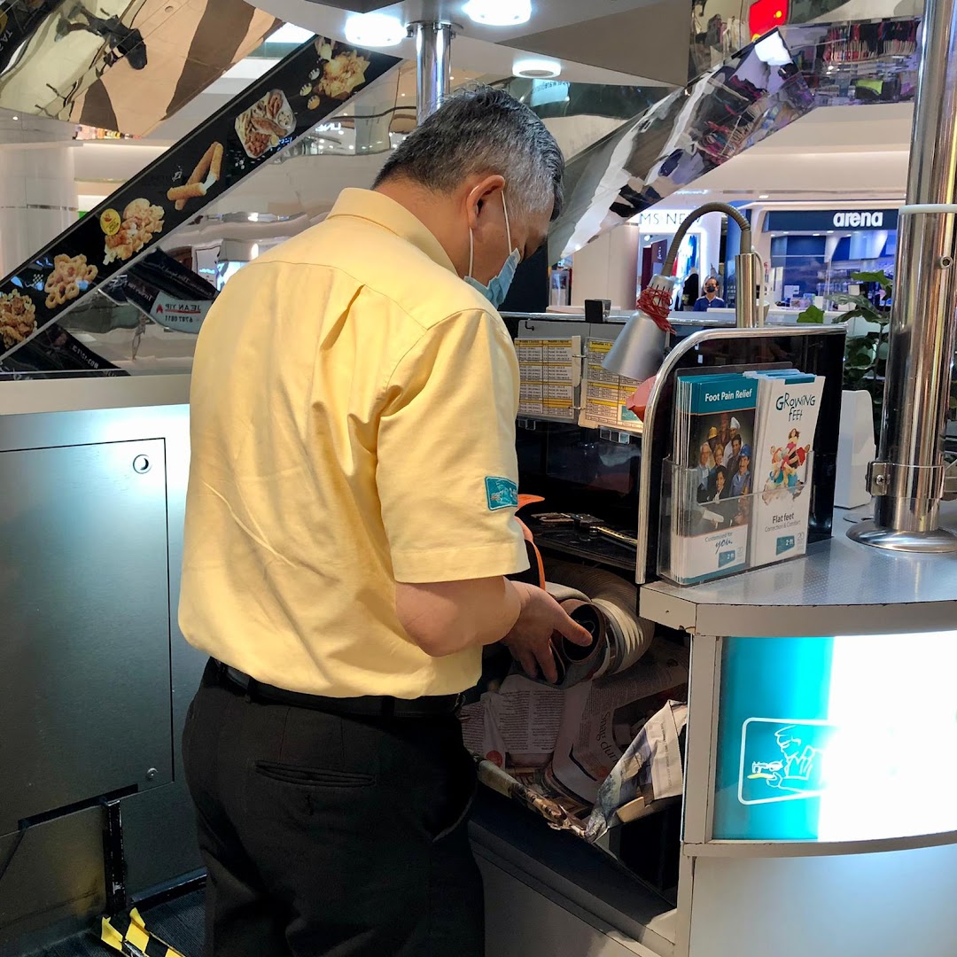 A staff member in a yellow shirt and mask works at the 2ft Orthotics kiosk.