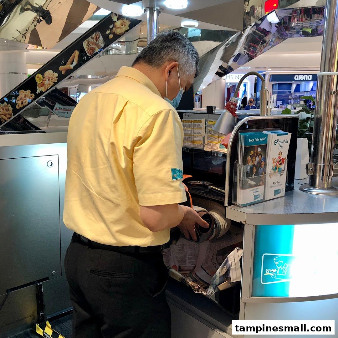 A staff member in a yellow shirt and mask works at the 2ft Orthotics kiosk.