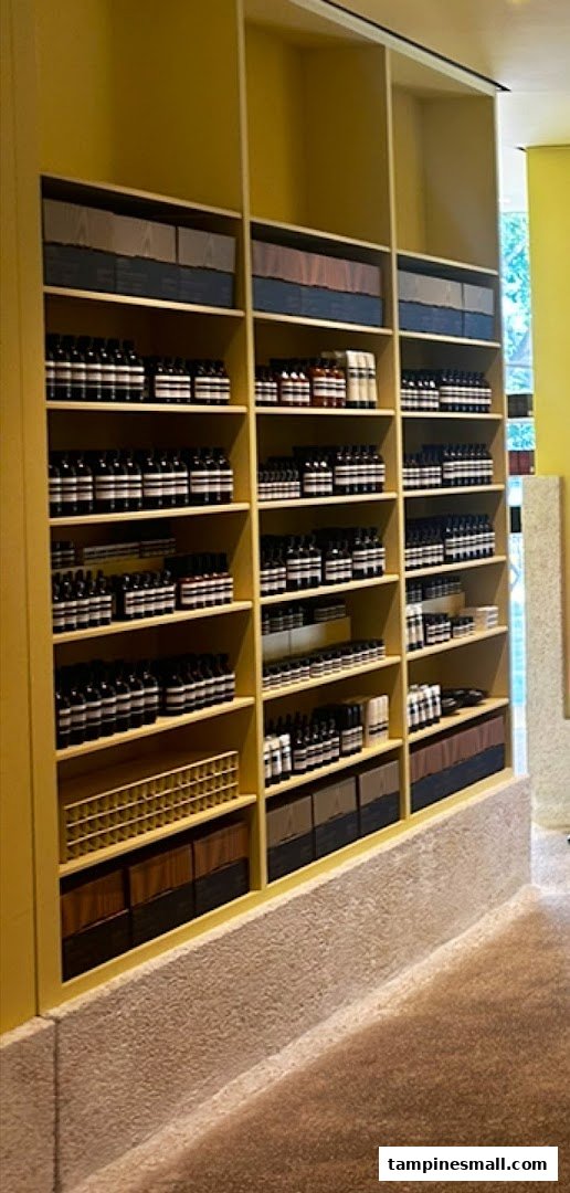 A well-organized display of Aesop skincare and body care products on yellow shelves inside the store.