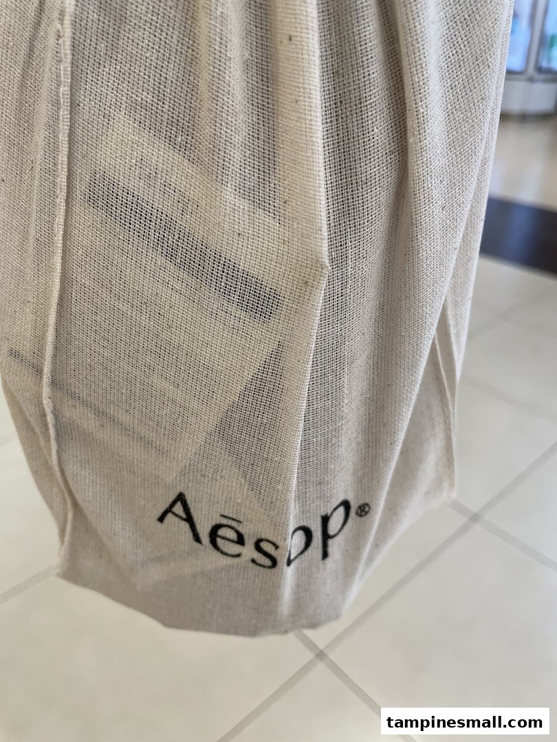 Close-up of a natural fabric Aesop branded reusable shopping bag.