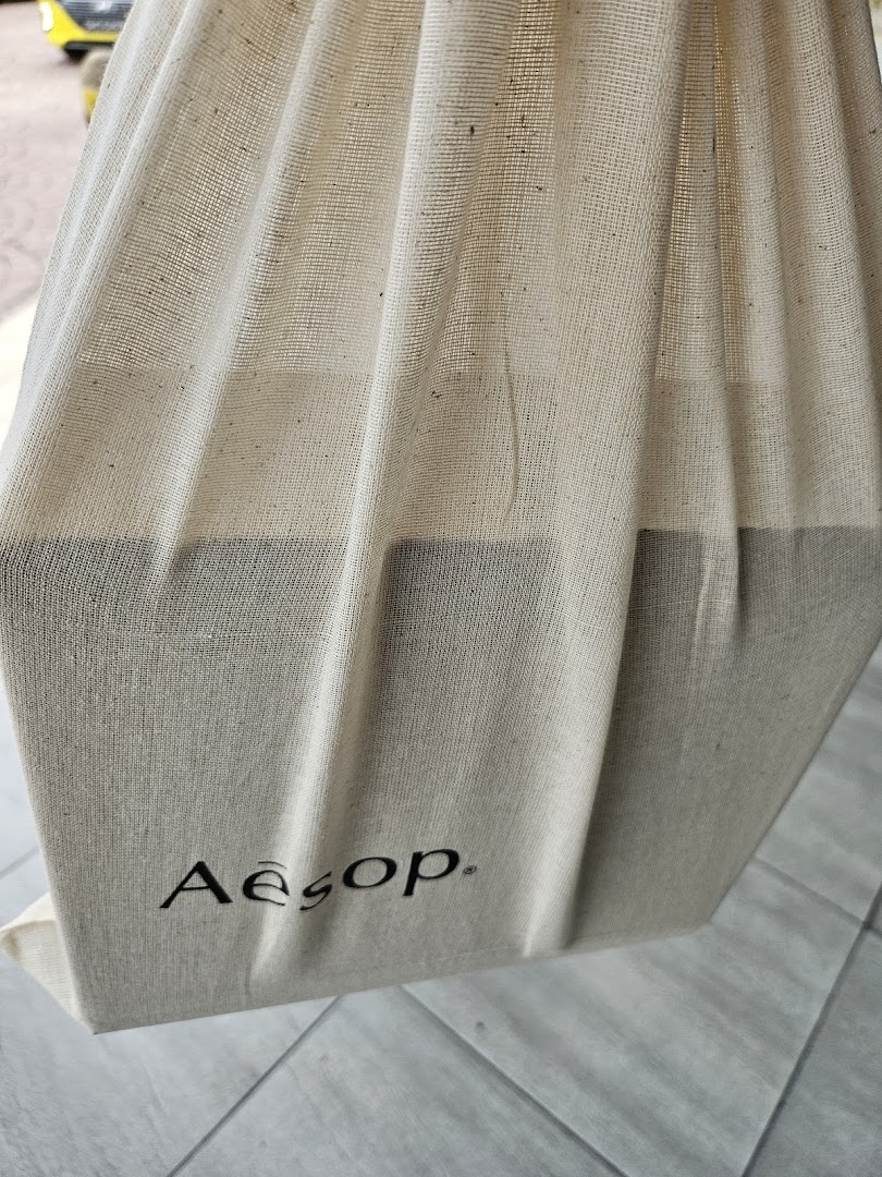 A close-up of an Aesop branded reusable fabric bag.