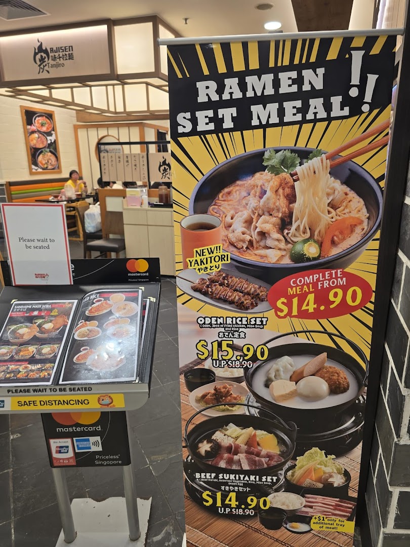 A promotional banner and stand displaying ramen and Japanese set meals with prices at Ajisen Tanjiro.