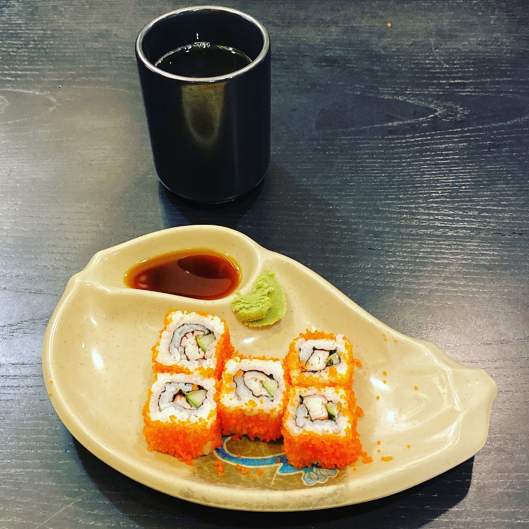 A plate of vibrant sushi rolls with soy sauce and wasabi, accompanied by a cup of tea.