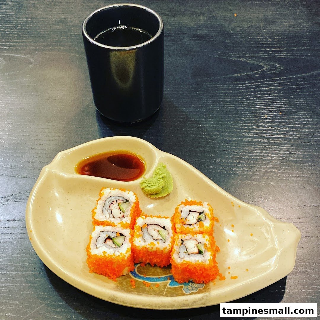 A plate of vibrant sushi rolls with soy sauce and wasabi, accompanied by a cup of tea.