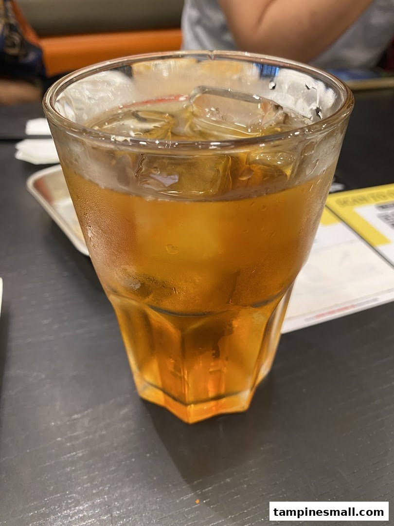 A refreshing glass of iced tea with ice cubes on a dark table.