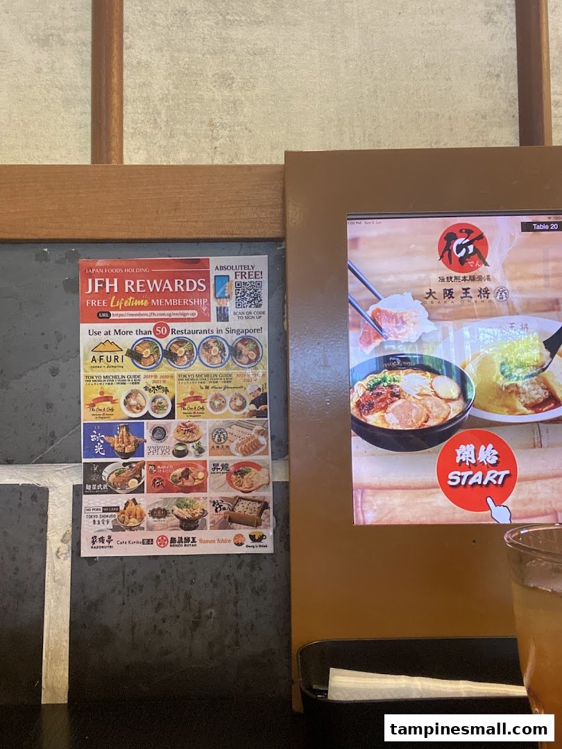 An in-store view featuring a digital ordering screen and a multi-brand loyalty program poster.