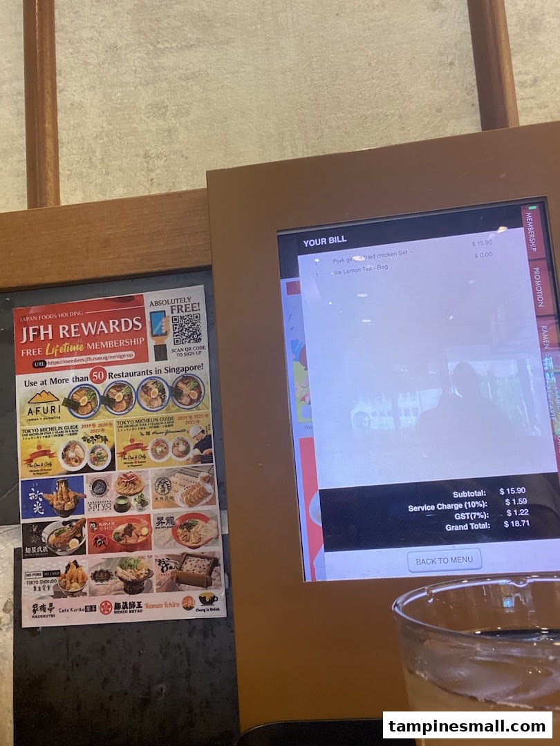 A digital ordering screen displaying a bill and a promotional poster for Japan Foods Holding rewards.