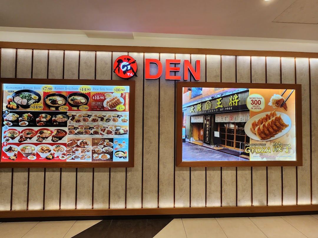 The shopfront of a Japanese eatery, featuring illuminated ramen and gyoza display boards.