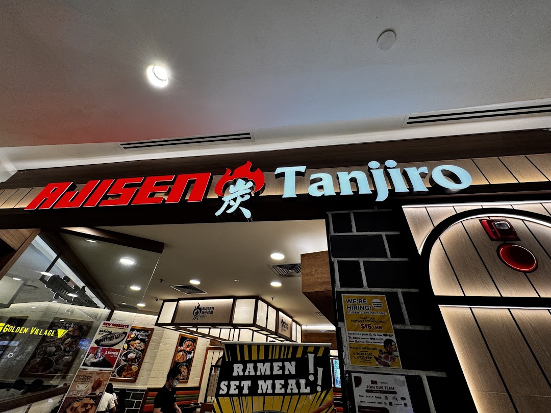The illuminated storefront of Ajisen Tanjiro, a ramen restaurant, with promotional posters visible.
