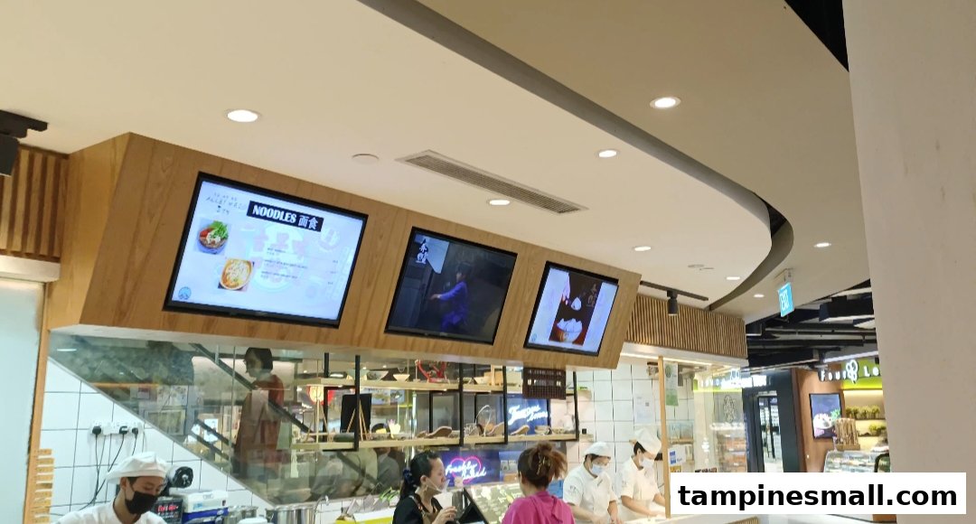 Staff prepare fresh noodles at Alley Wei's bustling food counter with digital menu displays.