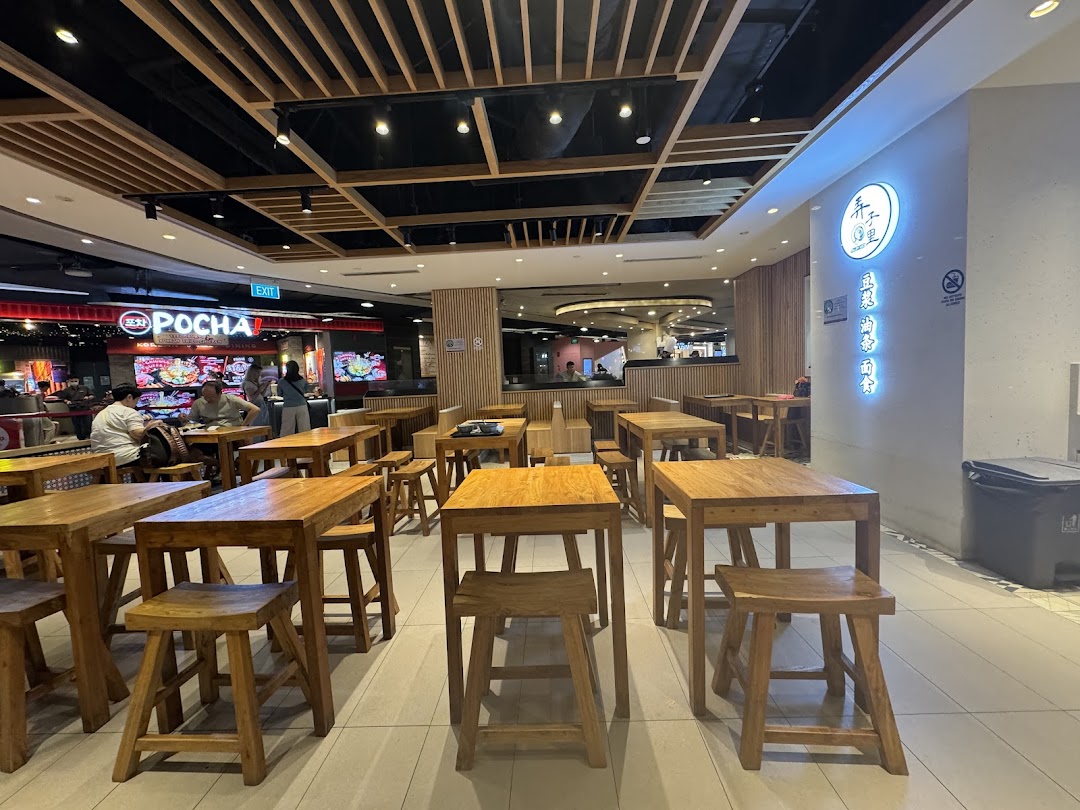 An inviting interior view of Alley Wei's dining area, featuring rustic wooden tables and stools under warm lighting.