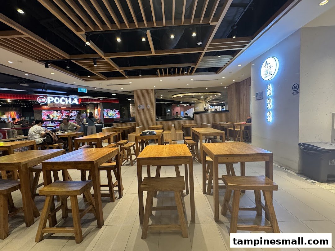 An inviting interior view of Alley Wei's dining area, featuring rustic wooden tables and stools under warm lighting.