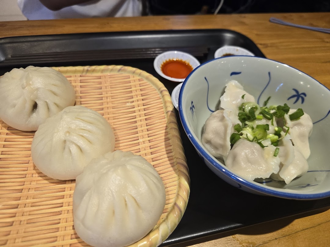 A close-up of delicious steamed buns and dumplings served with dipping sauces at Alley Wei.
