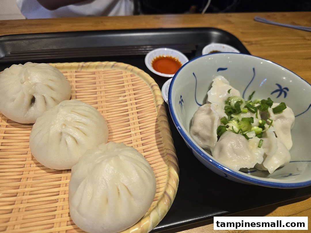 A close-up of delicious steamed buns and dumplings served with dipping sauces at Alley Wei.