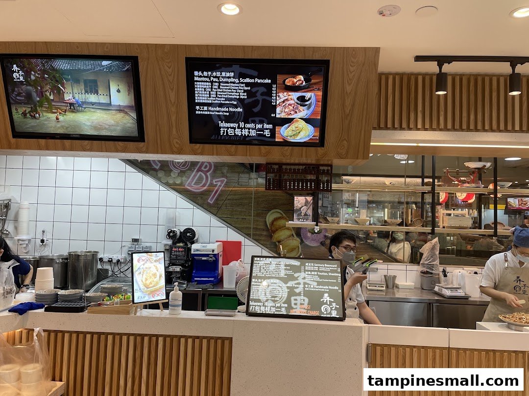 A bustling counter at Alley Wei, showcasing staff preparing Chinese dishes and digital menu boards.