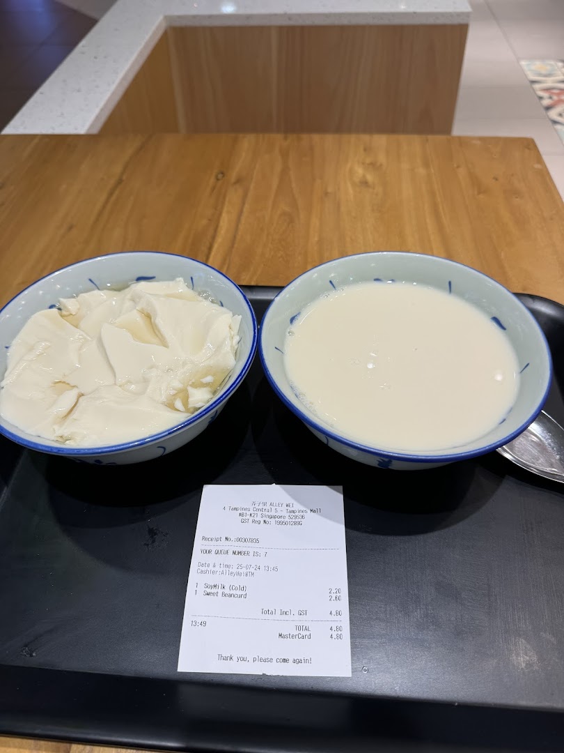 Two bowls of traditional Asian desserts, beancurd and soymilk, served on a tray with a receipt.