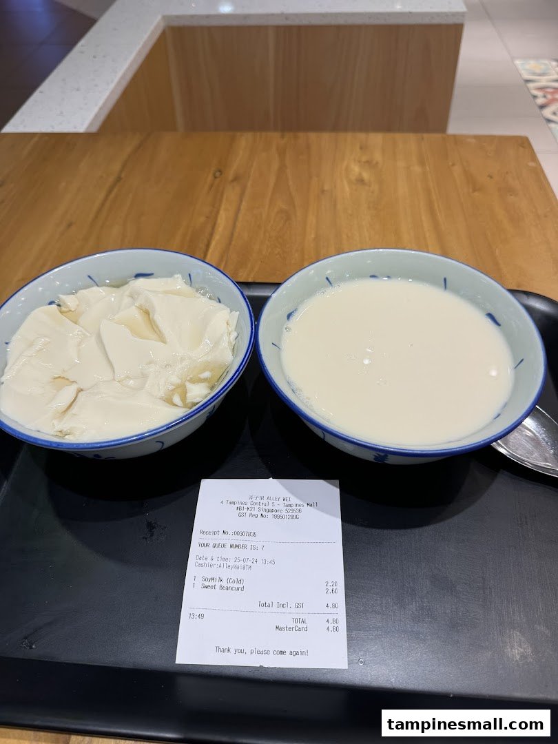 Two bowls of traditional Asian desserts, beancurd and soymilk, served on a tray with a receipt.