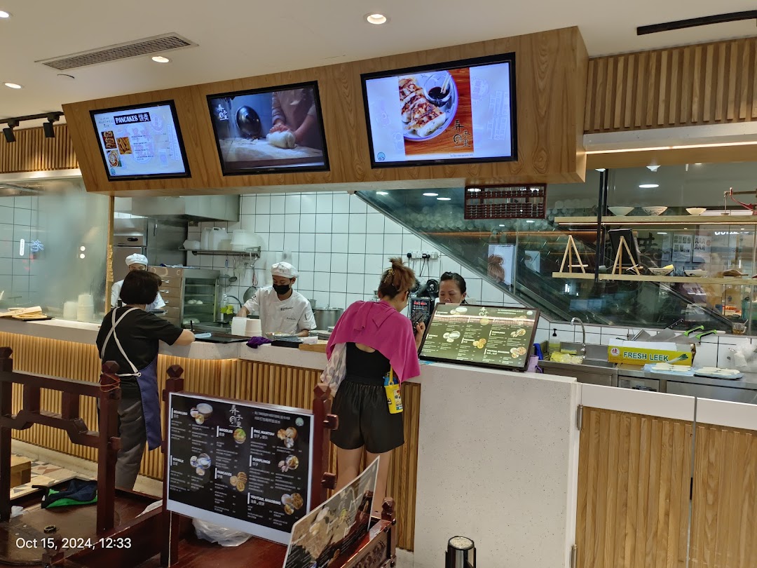 Inside Alley Wei, staff prepare fresh food at the counter while customers order, showcasing an open kitchen.