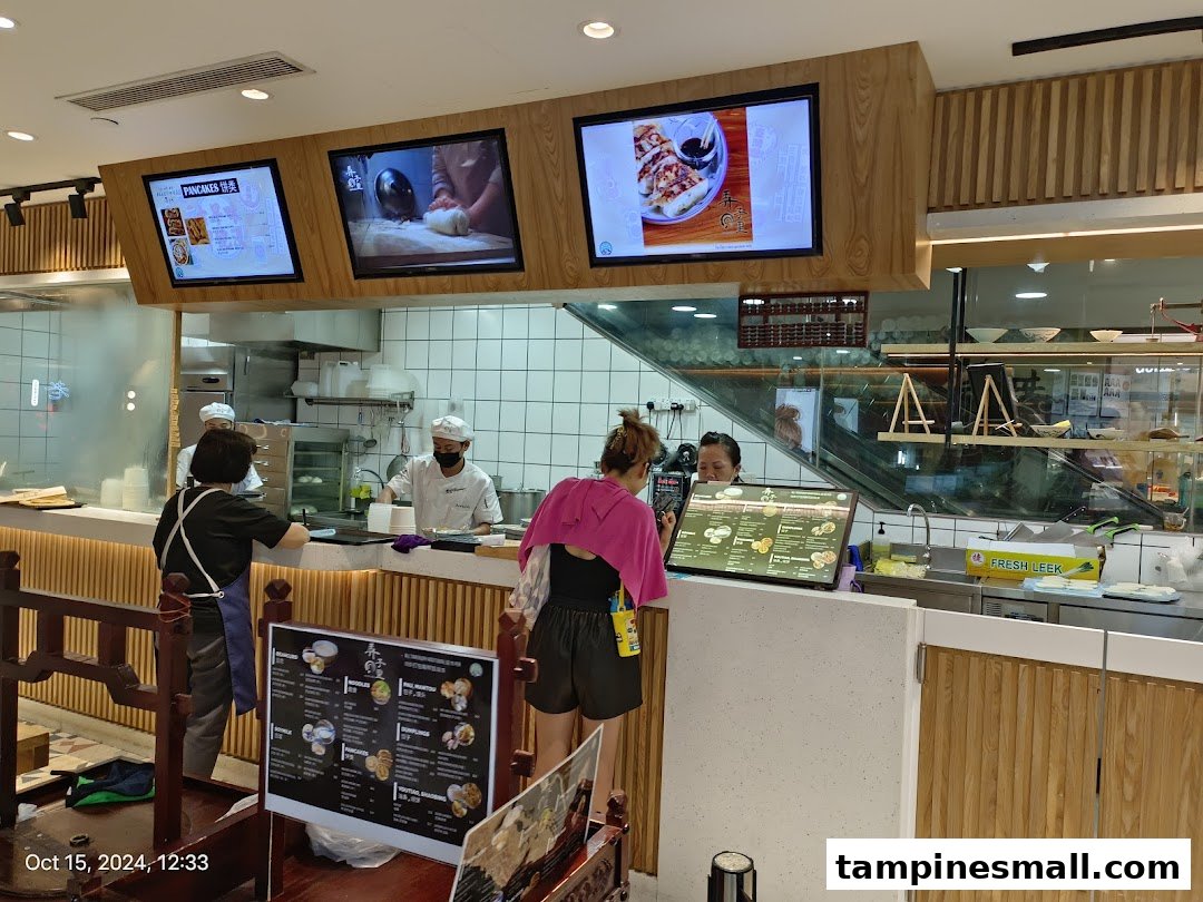 Inside Alley Wei, staff prepare fresh food at the counter while customers order, showcasing an open kitchen.