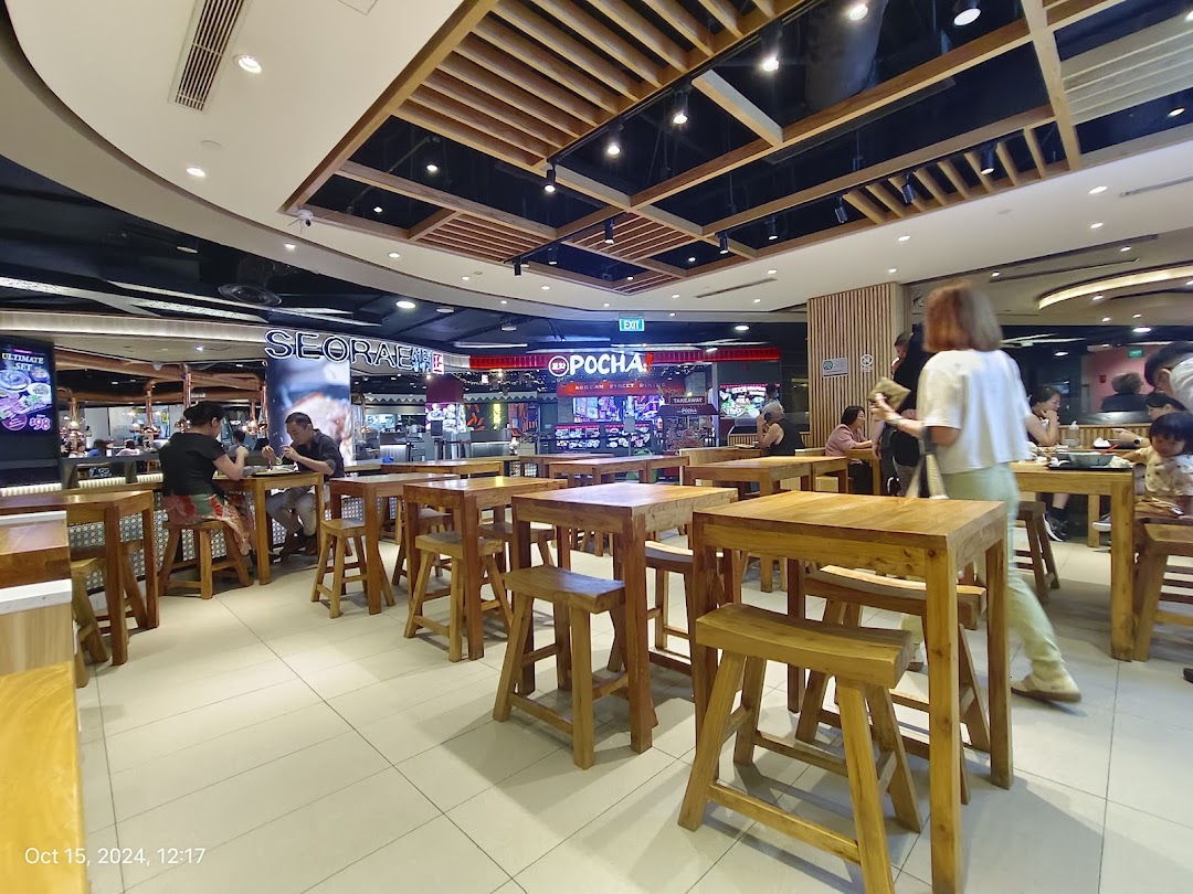 A bustling interior view of a modern dining area with wooden tables and patrons enjoying meals.