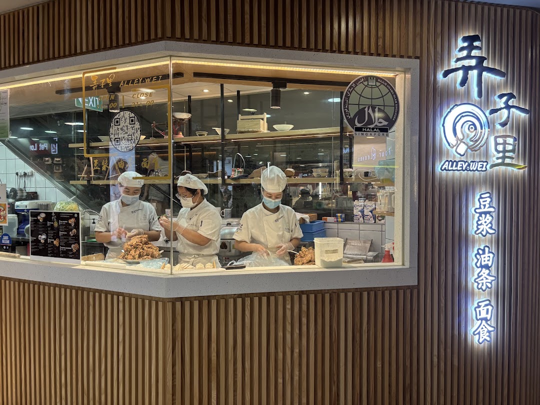 Alley Wei shop front with chefs preparing food behind a glass counter, featuring the illuminated sign.