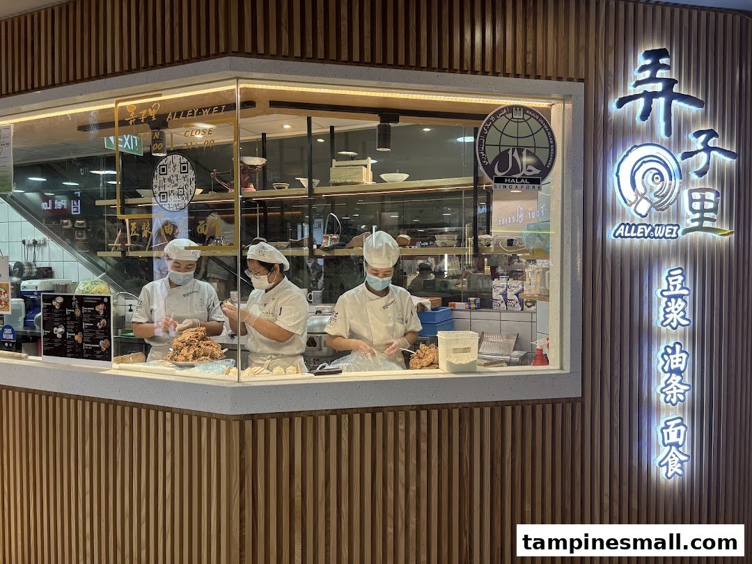 Alley Wei shop front with chefs preparing food behind a glass counter, featuring the illuminated sign.