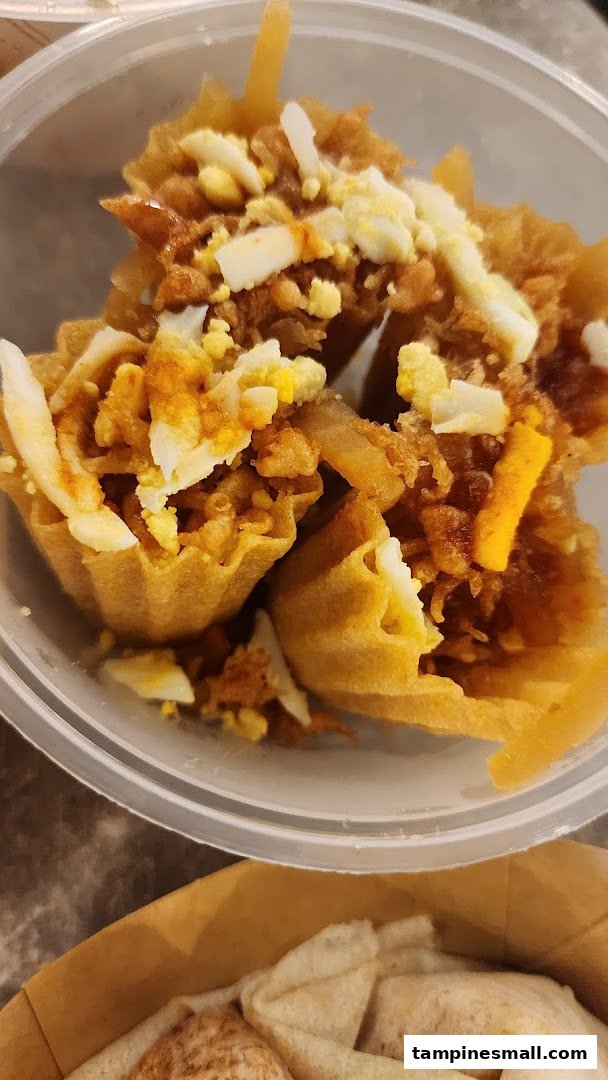 A close-up of several crispy golden tart shells filled with savory ingredients and topped with chopped egg.