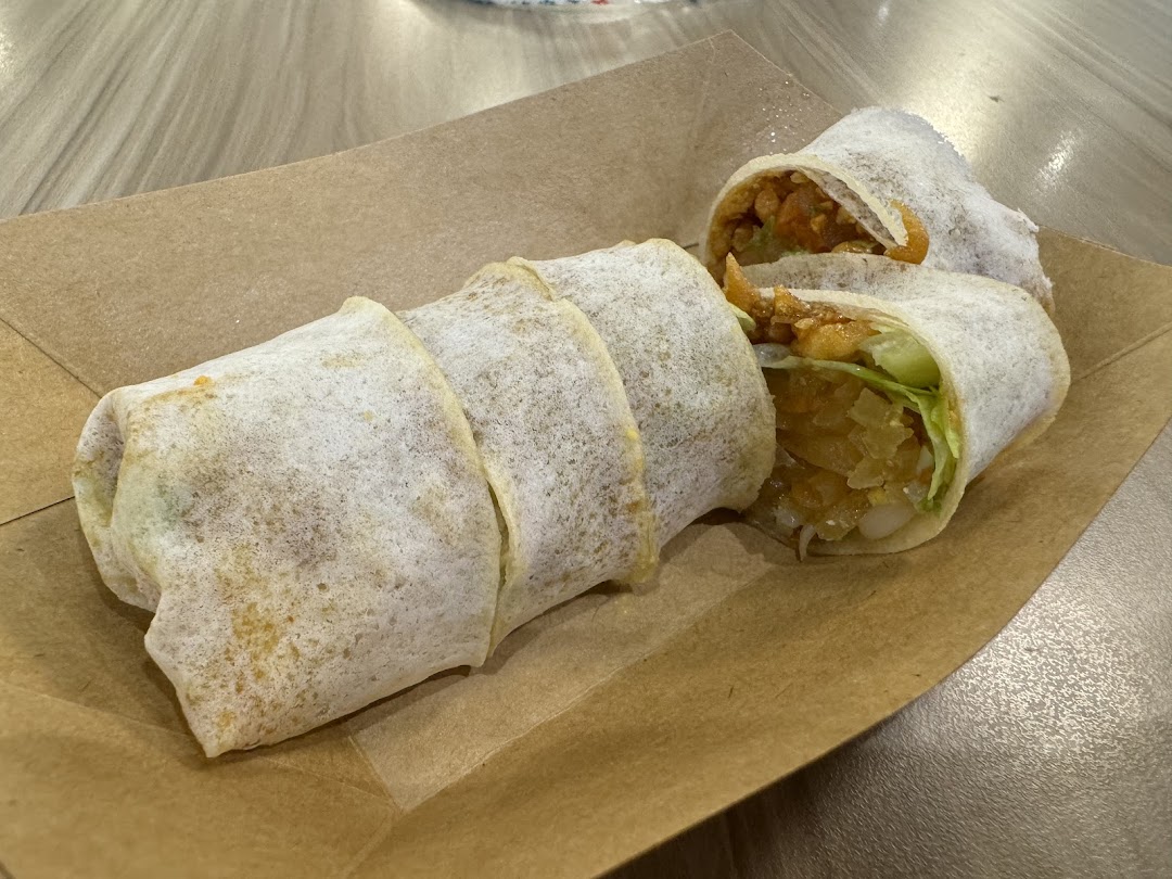 Freshly prepared popiah (spring rolls) served in a brown paper tray.
