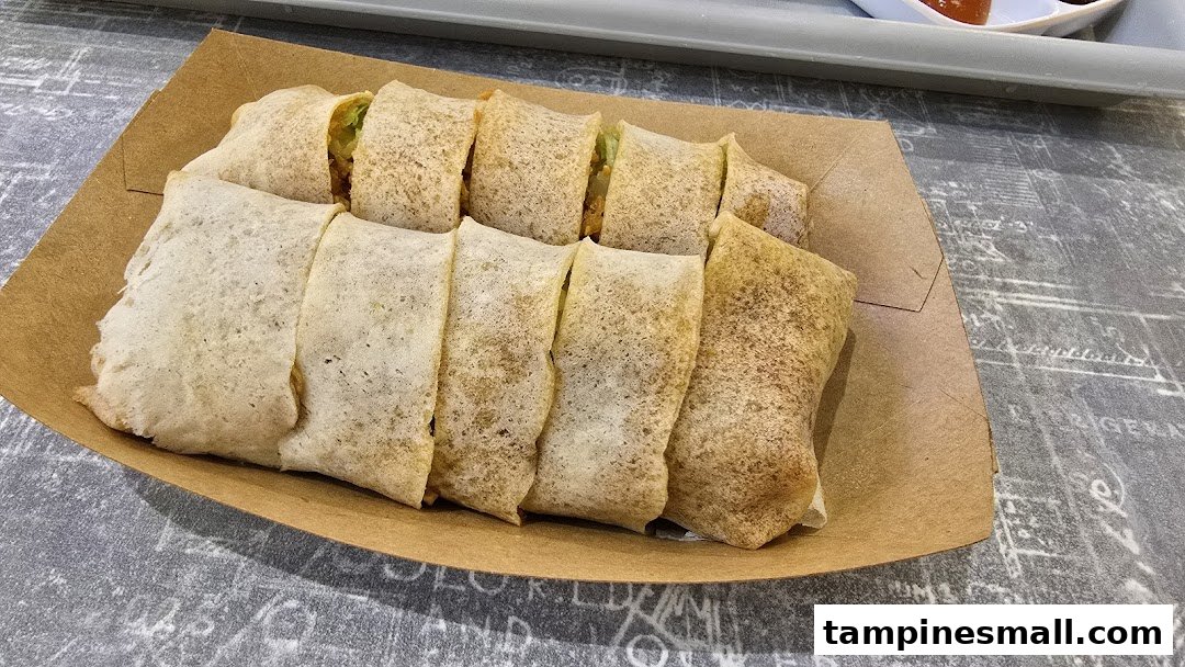 A close-up of freshly prepared popiah rolls served in a brown paper tray.