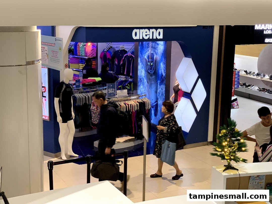 The image shows the entrance of the Arena sportswear shop with customers passing by.