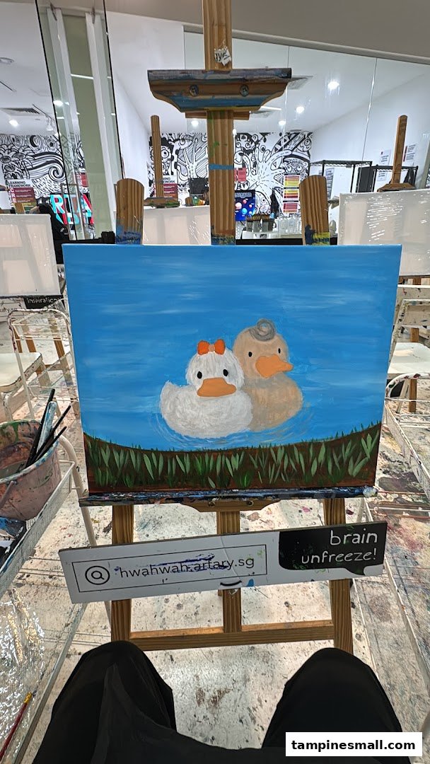 A charming painting of two ducks on an easel inside an art studio, with creative wall art in the background.