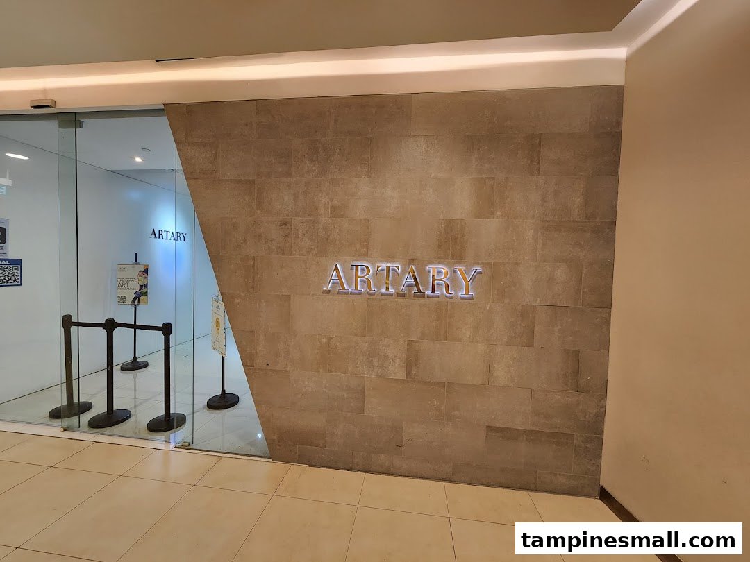 The modern entrance of ARTARY Tampines Mall, featuring its prominent illuminated logo and glass doors.
