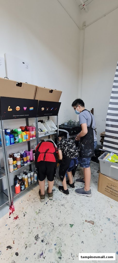 People selecting colorful paints and art tools in an art studio.