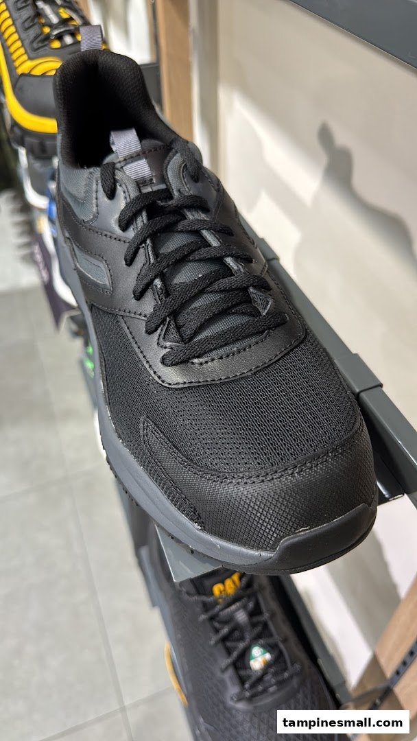 Close-up of a black athletic shoe displayed on a retail shelf, showcasing its texture and design.