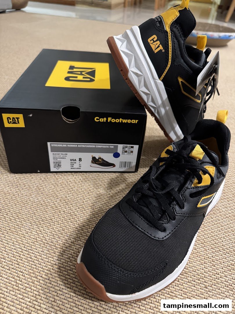 A pair of black and yellow CAT Footwear sneakers with their matching shoebox.