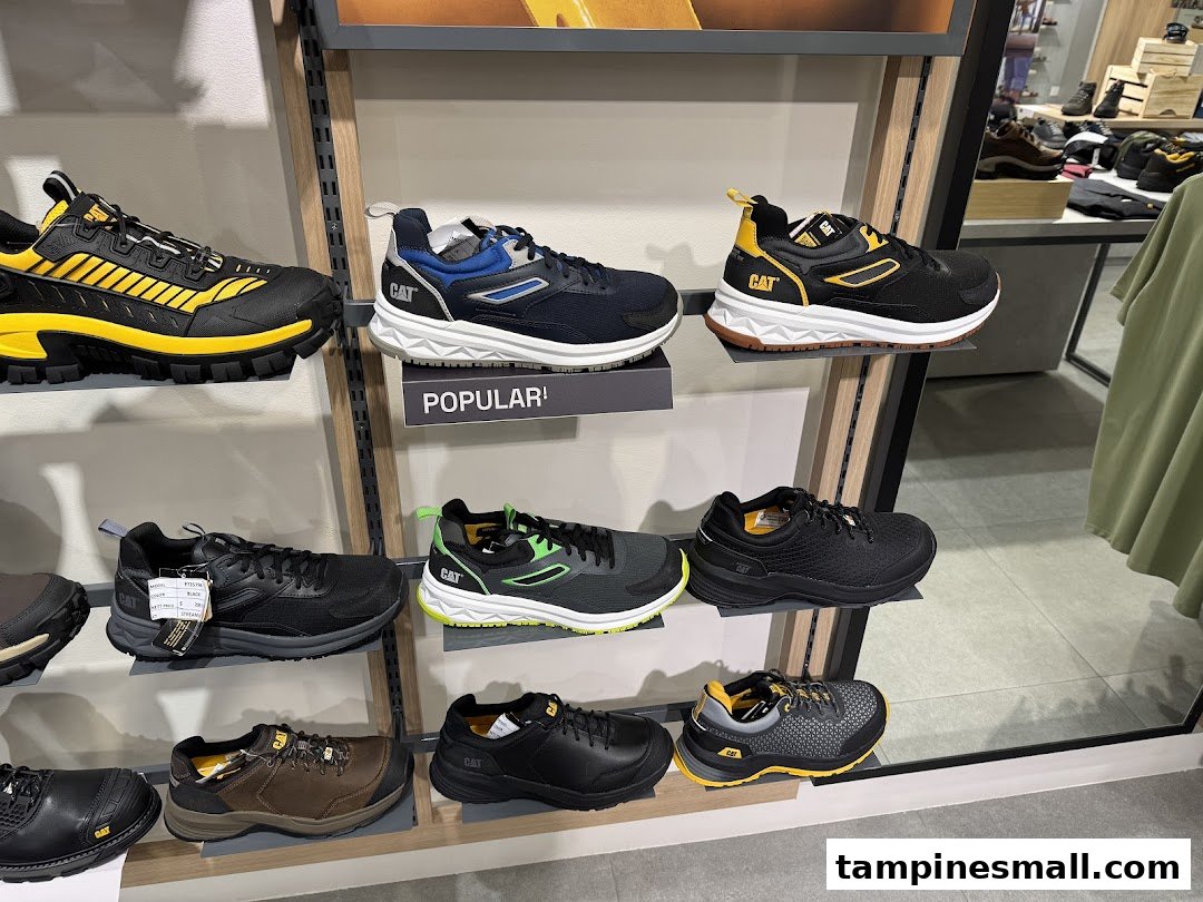 A display of various CAT brand footwear, including sneakers and work boots, in a retail store.