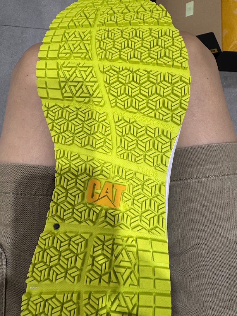 Close-up of a bright green shoe sole featuring a CAT logo and advanced slip resistance technology.