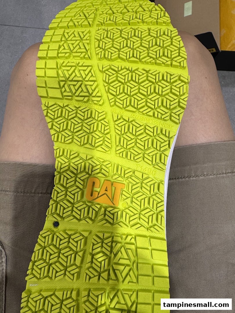 Close-up of a bright green shoe sole featuring a CAT logo and advanced slip resistance technology.