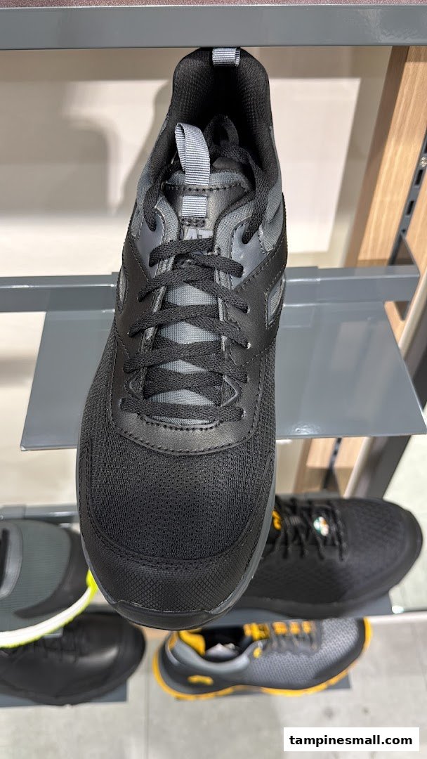 A close-up of a black athletic shoe displayed on a shelf in a retail store.