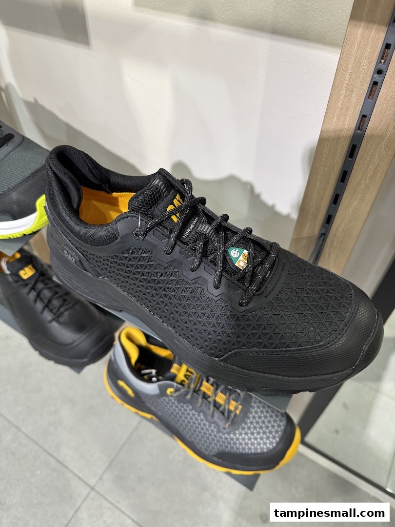 Close-up of black CAT brand shoes with yellow accents displayed in a retail store.