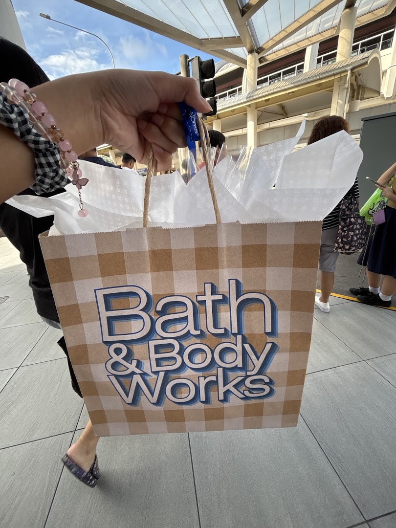 A person holds a Bath & Body Works shopping bag with a brown and white plaid design.