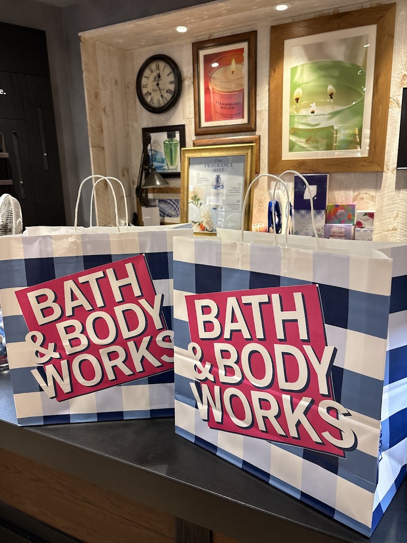 Two Bath & Body Works shopping bags on a counter, with store decor and product displays in the background.