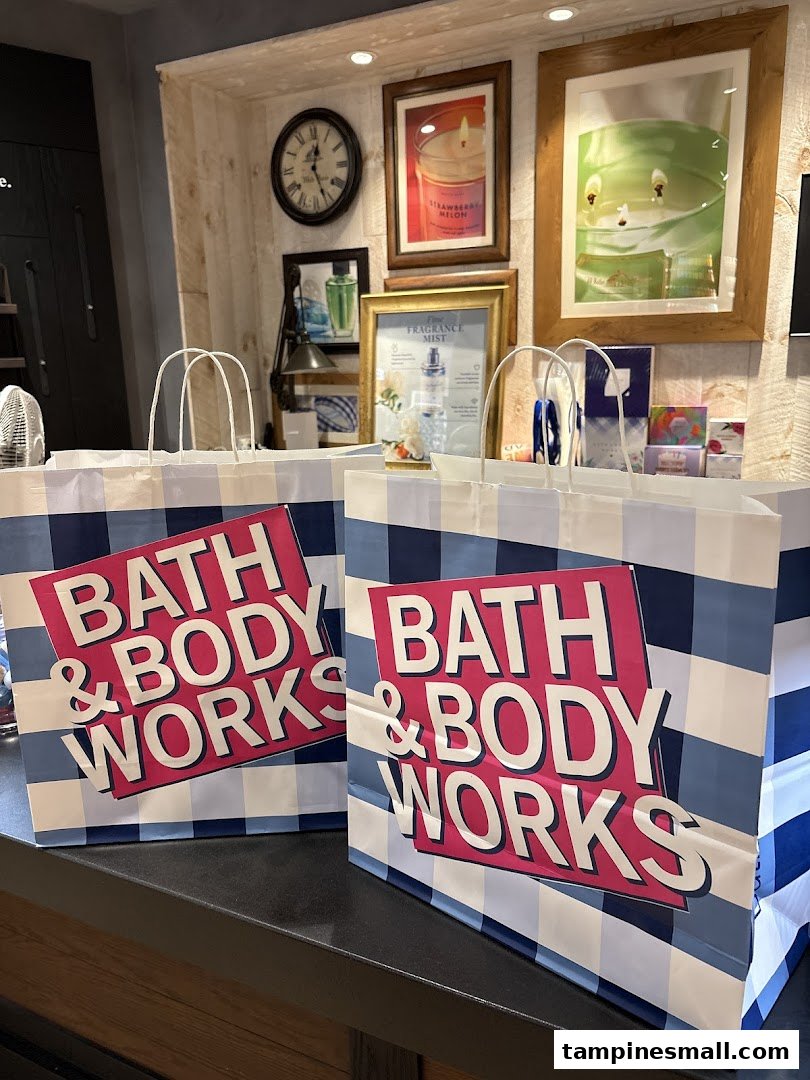Two Bath & Body Works shopping bags on a counter, with store decor and product displays in the background.