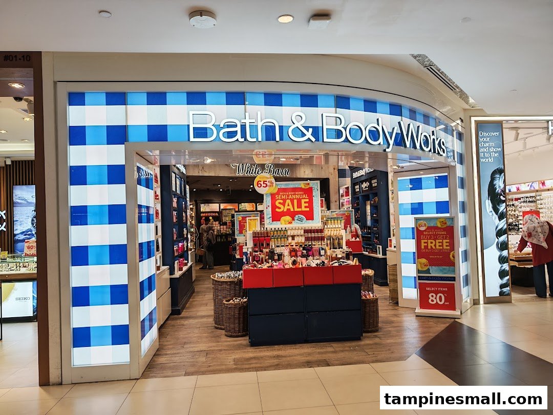 The Bath & Body Works shop front at Tampines Mall, featuring its iconic blue and white checkered design and prominent sale signs.