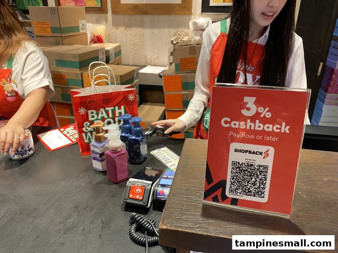 A Bath & Body Works checkout counter with staff, products, and a ShopBack cashback sign.