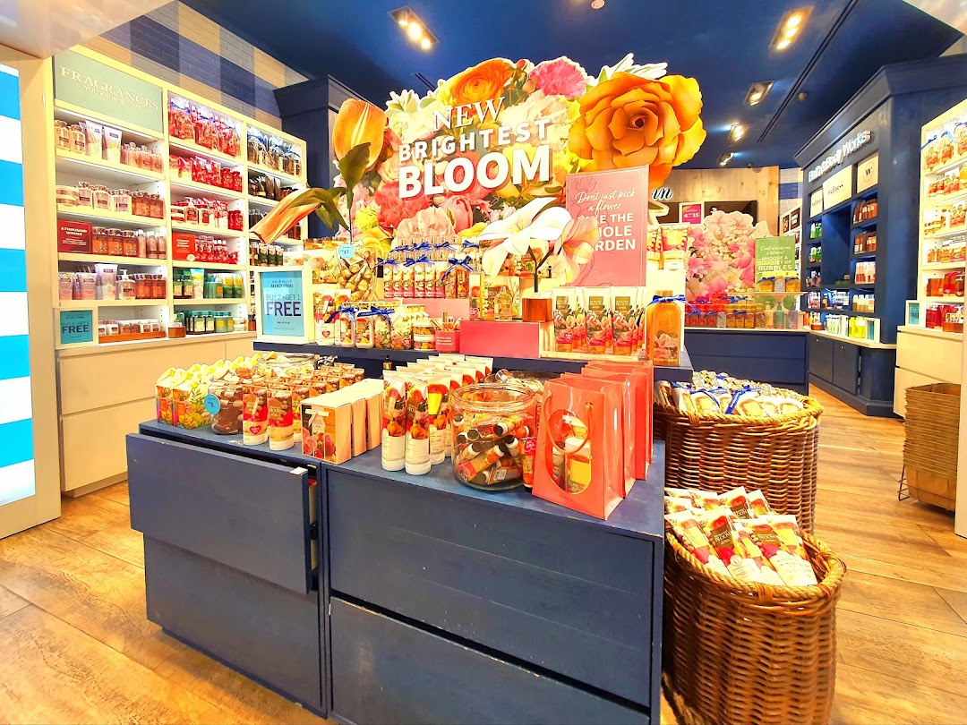 Vibrant interior of Bath & Body Works, showcasing a 'New Brightest Bloom' display with various fragranced products.