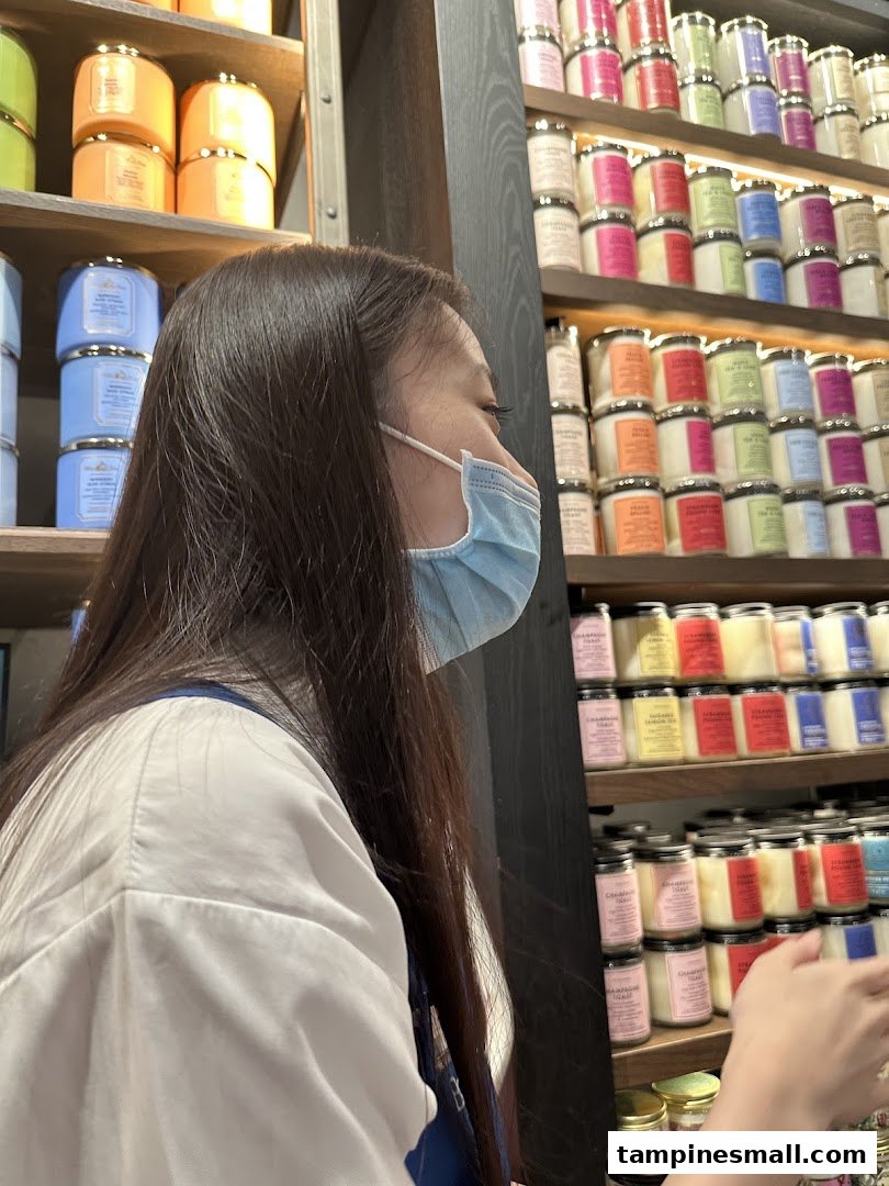 A customer wearing a mask browses colorful candles and body care products on shelves at Bath & Body Works.
