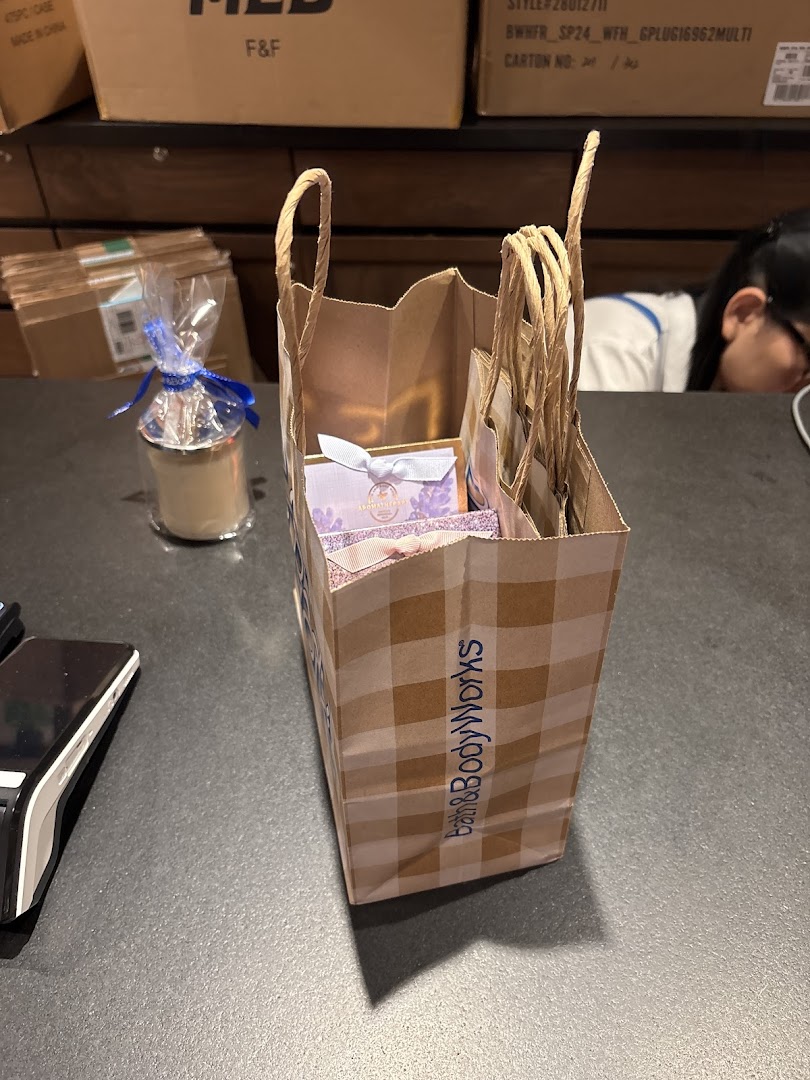 A Bath & Body Works shopping bag filled with products on a store counter.