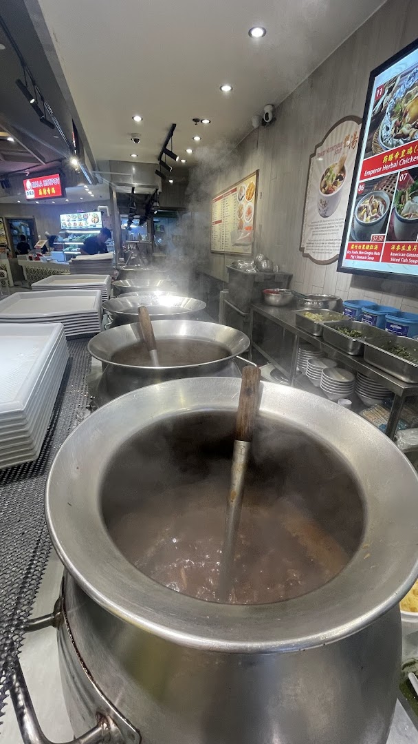 Large steaming pots of traditional Chinese soups at a food stall, ready to serve customers.