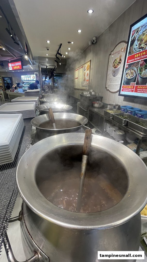 Large steaming pots of traditional Chinese soups at a food stall, ready to serve customers.
